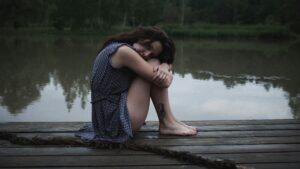 Mujer sentada en un muelle reflexionando, duelo perinatal y pérdida