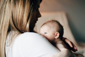Madre con depresión posparto abrazando a su bebé recién nacido, gesto protector