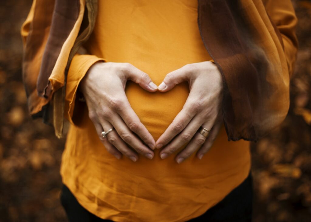 Anxiety in pregnancy: hands forming a heart shape over a pregnant woman's belly