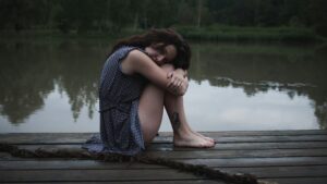 Woman sitting on a dock reflecting, representing perinatal grief and loss