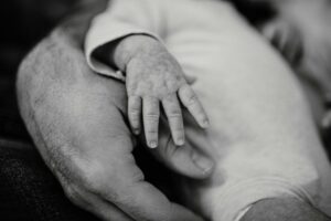 Tiny baby hand resting on father's hand, representing fatherhood and mental health in the perinatal period